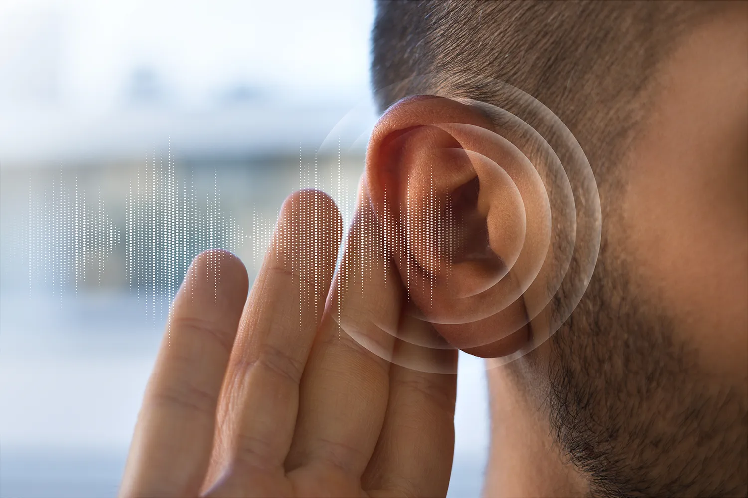 Close-up of a person holding a hand near their ear with sound wave graphics illustrating hearing.