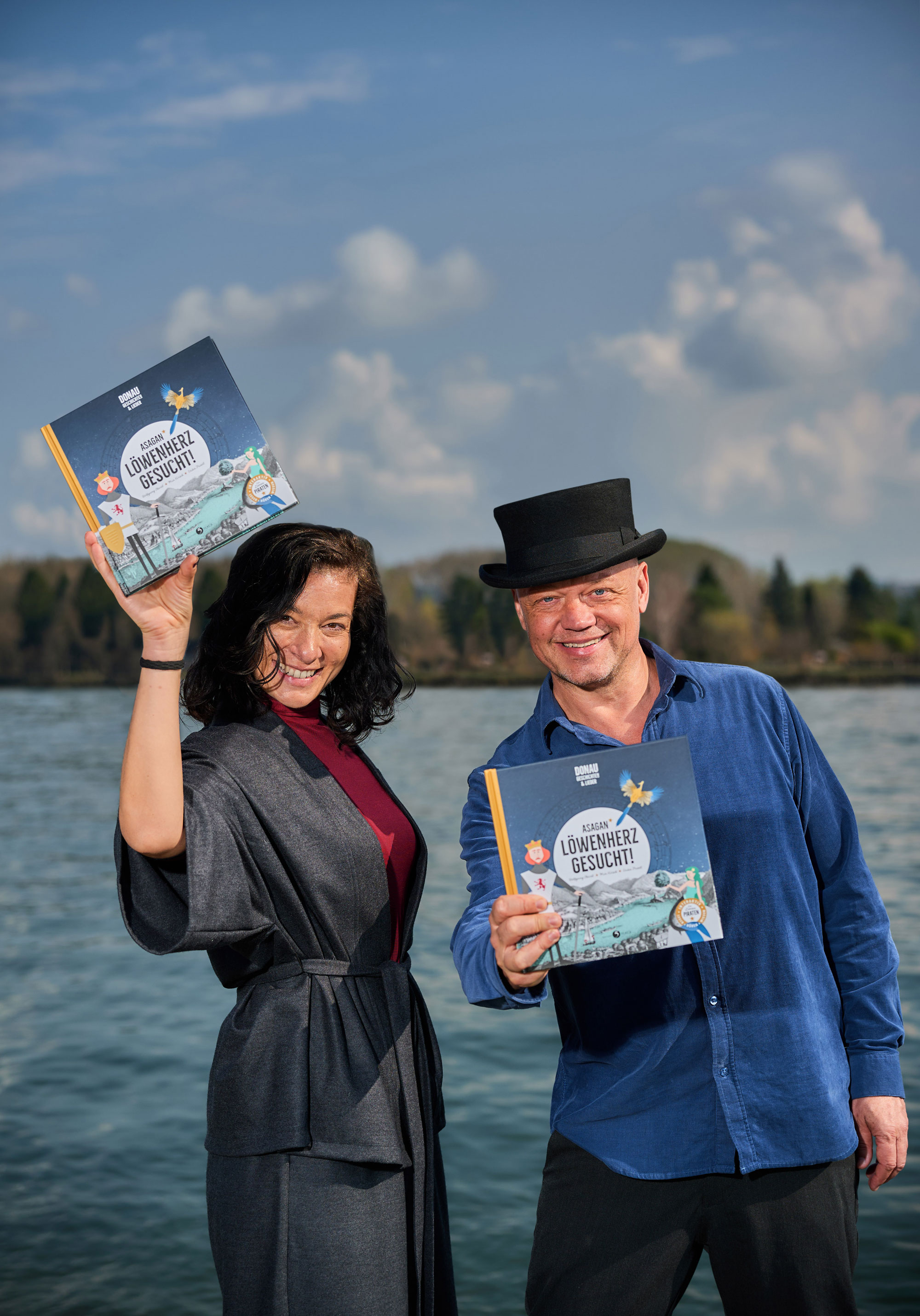 Magda Hassan und Wolfgang Hartl mit Buch vor einem See Stehend