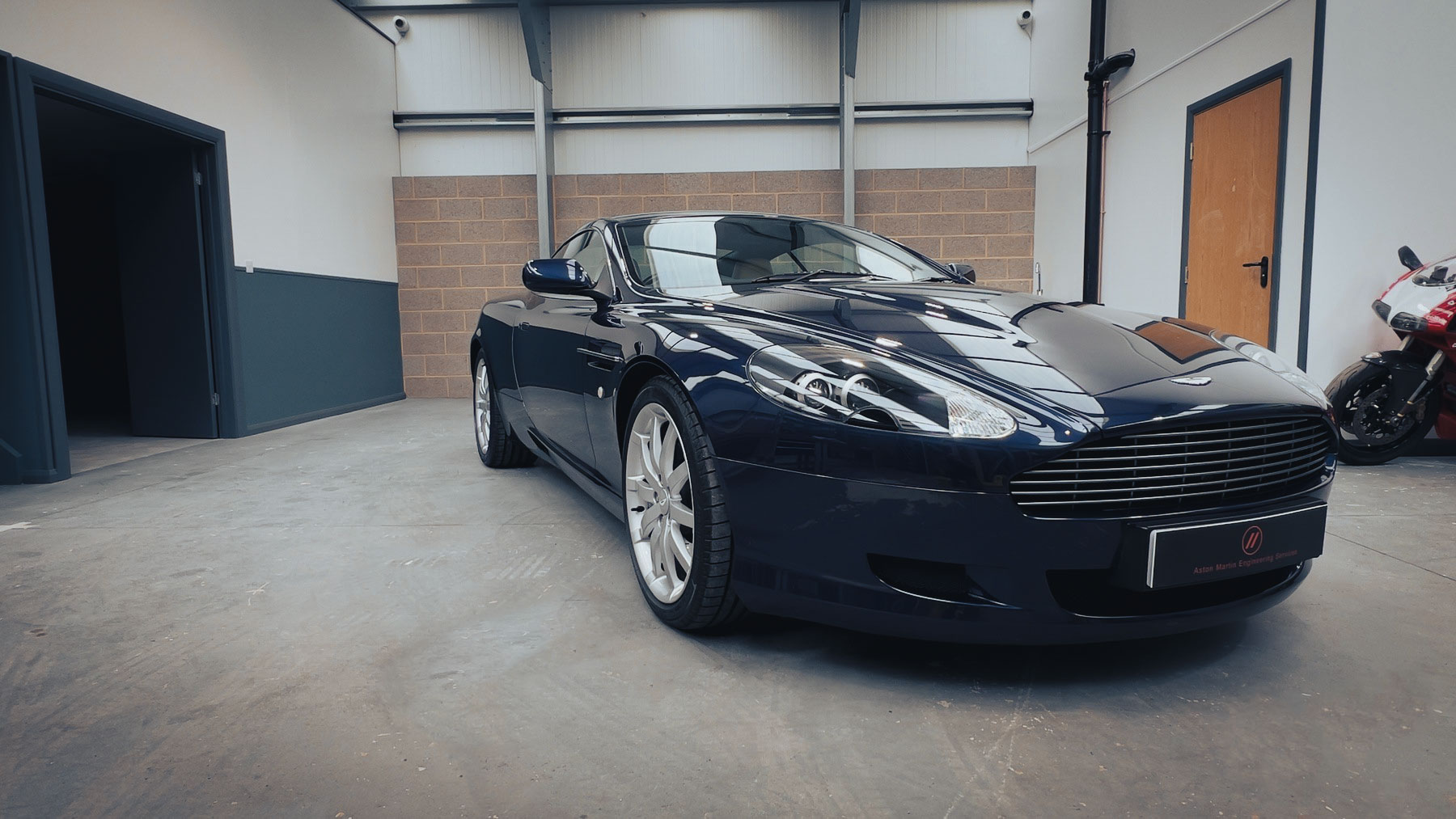 2004 Aston Martin DB9 in Blue Sapphire Metallic, front three-quarter view in the Hutson Engineering workshop