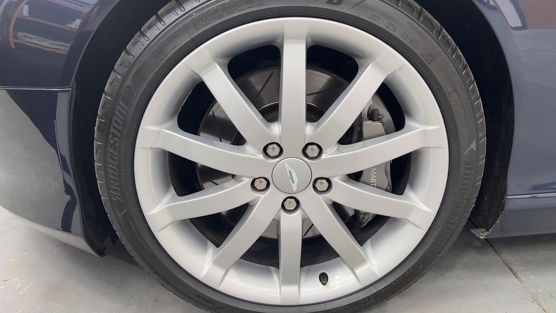 Silver ten-spoke alloy wheel and brake disc on the Aston Martin DB9