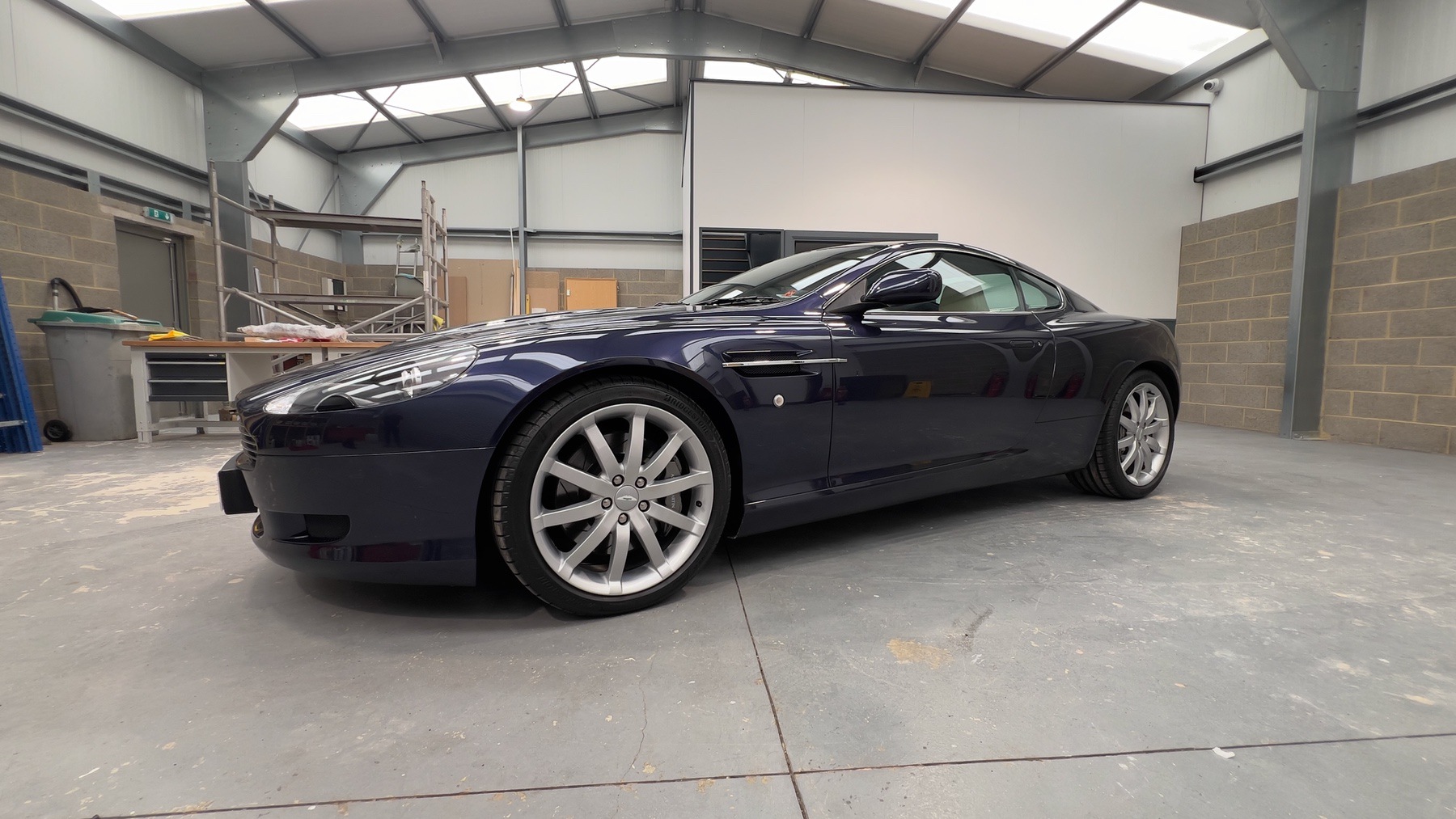 Side profile of the Blue Sapphire Metallic Aston Martin DB9 on silver ten-spoke alloy wheels