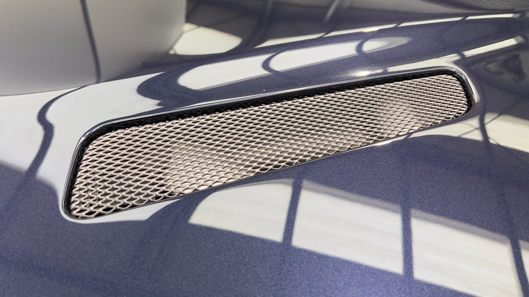 Mesh bonnet vent set into the Aston Martin DB9's Blue Sapphire Metallic bodywork