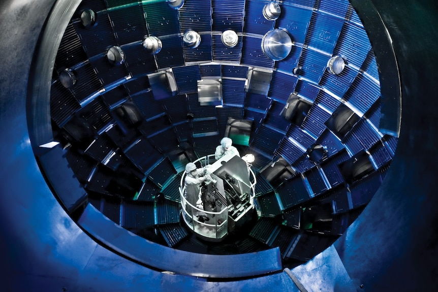 Two people in full white suits standing inside a blue sphere