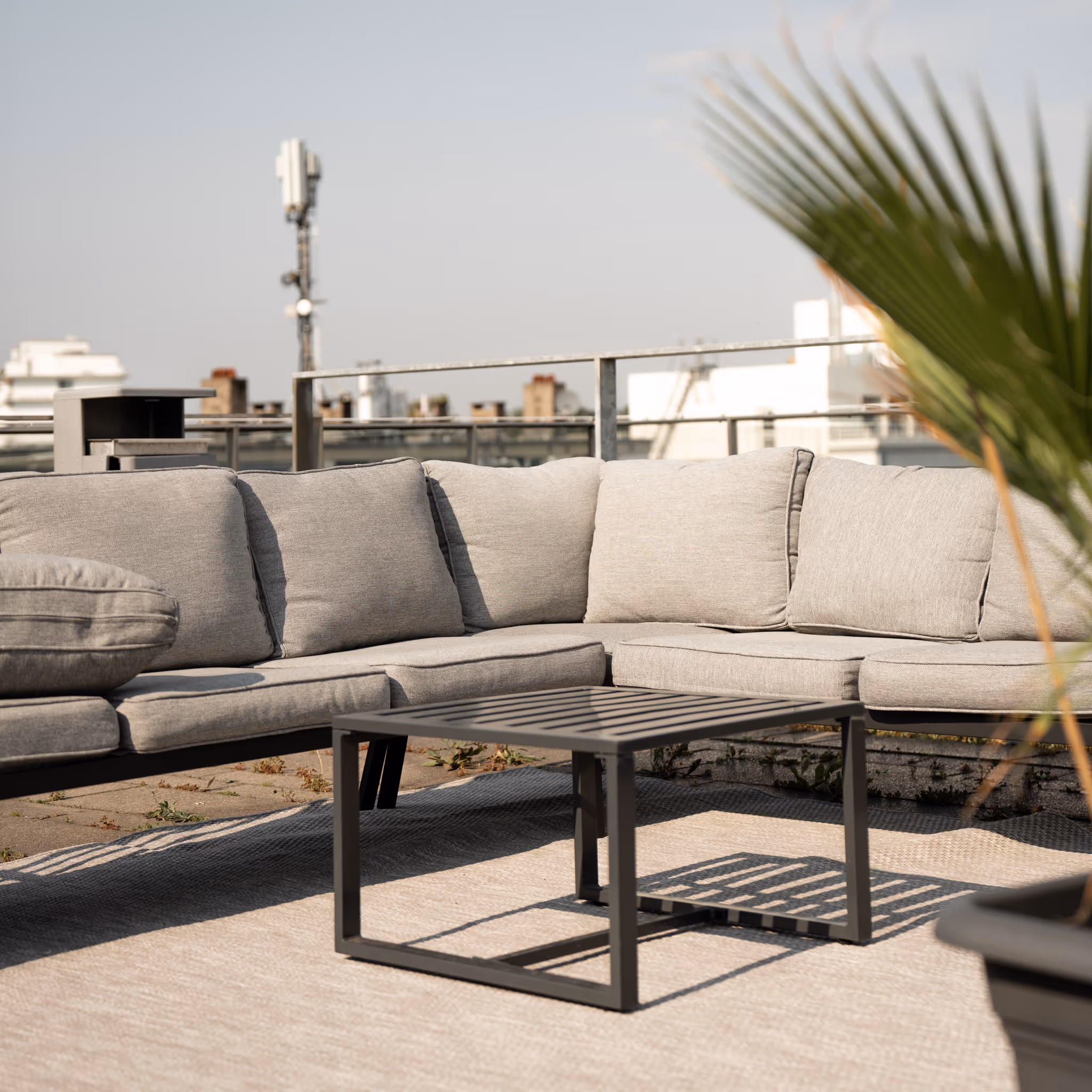 A large grey couch with a black table in front of it.
