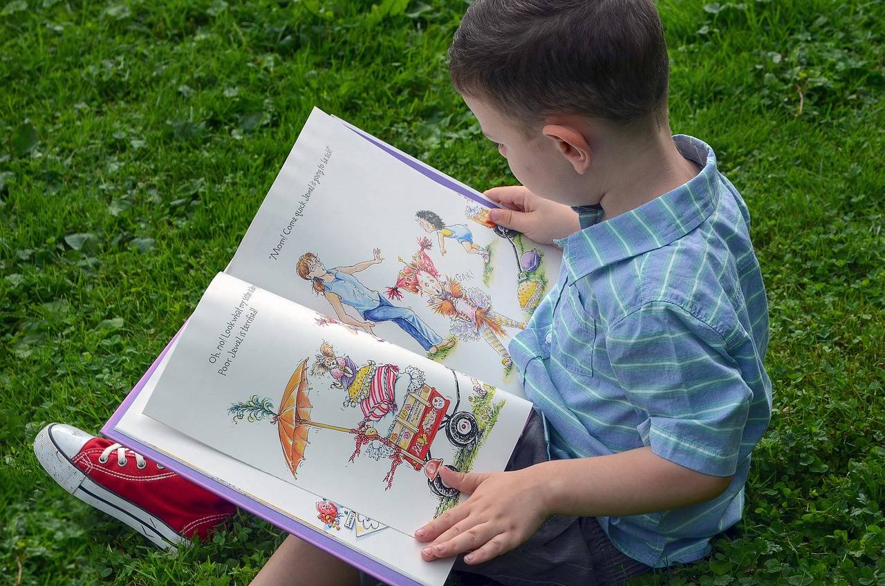 Un garçon lisant un livre assis dans la pelouse