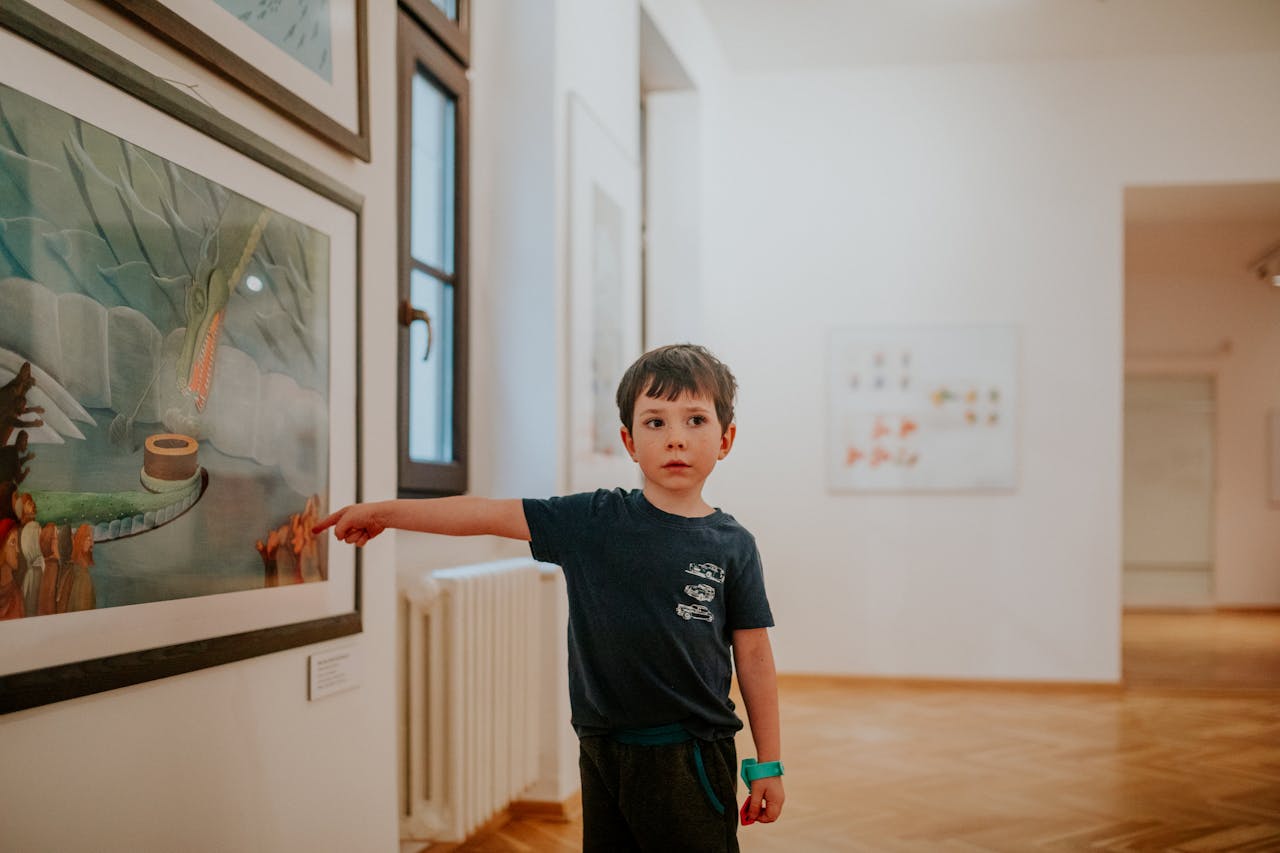 Un jeune garçon est dans un musée et mon un tableau du doigt