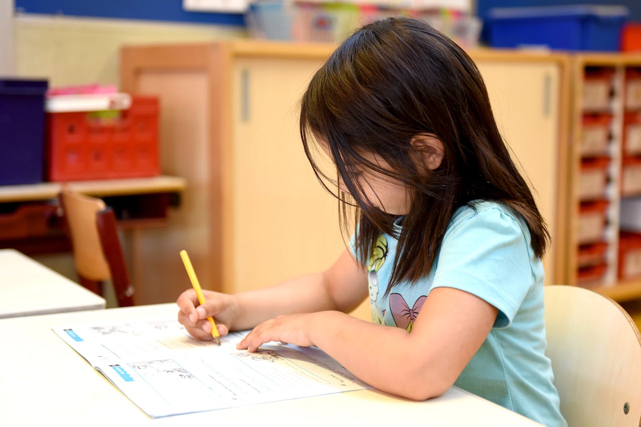 Une jeune fille fait des activités dans un magazine, elle est sur un petit bureau en salle de classe