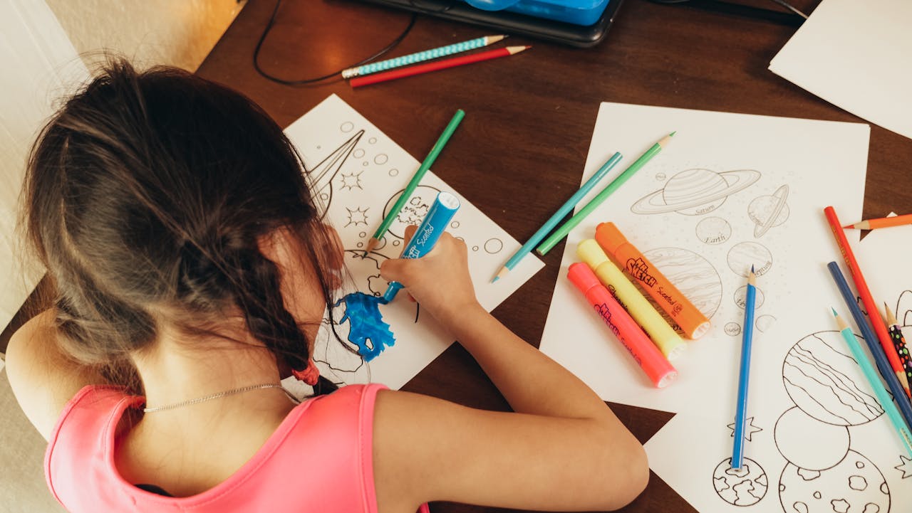 Une jeune fille en pleine création artistique, elle fait des coloriages avec des feutres et des crayons