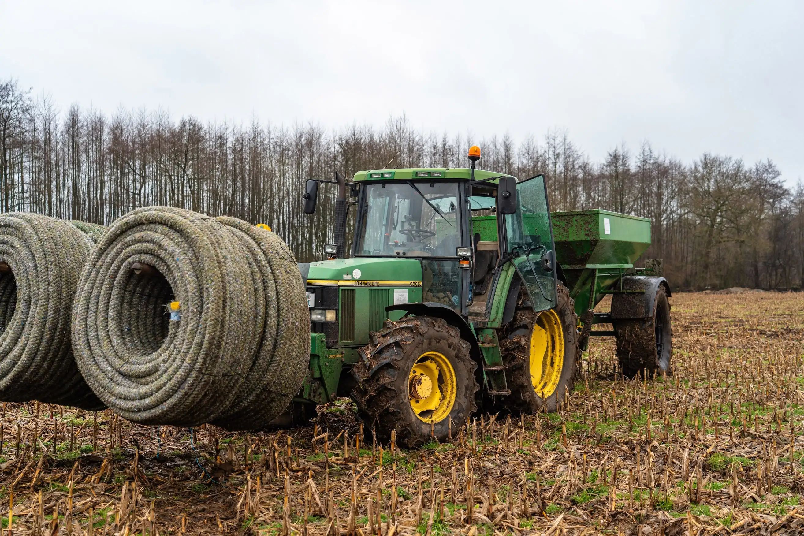A green tractor with a yellow front wheel and a yellow and black front tire.