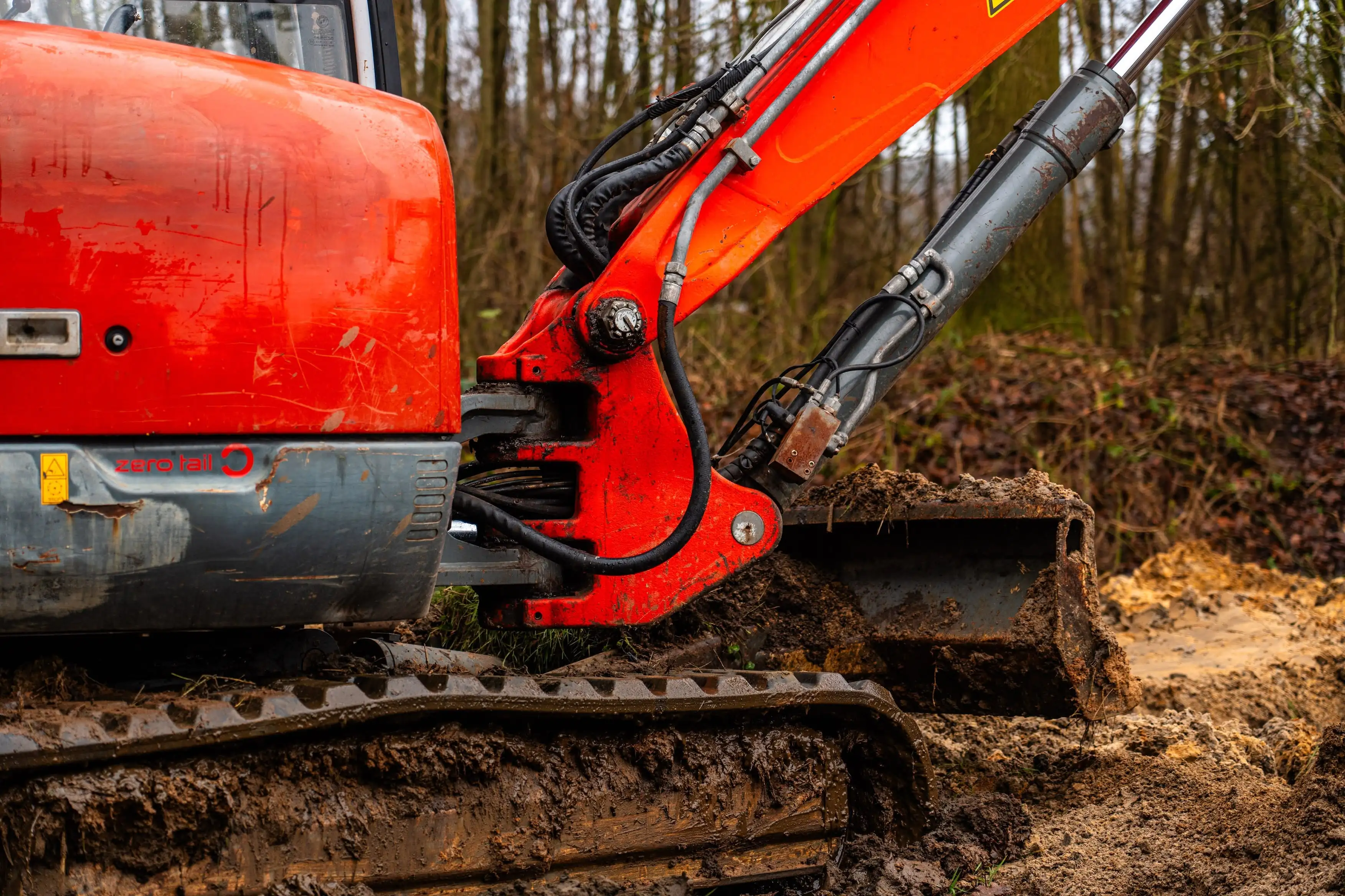 A large red excavator digging in the dirt.