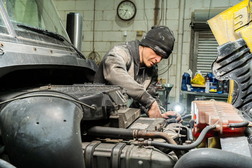 mechanic fixing a truck with the hood open