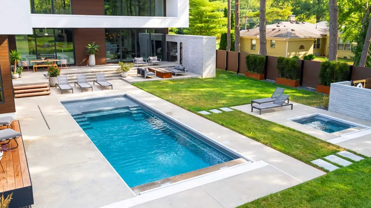 A backyard with a swimming pool and lounge chairs.