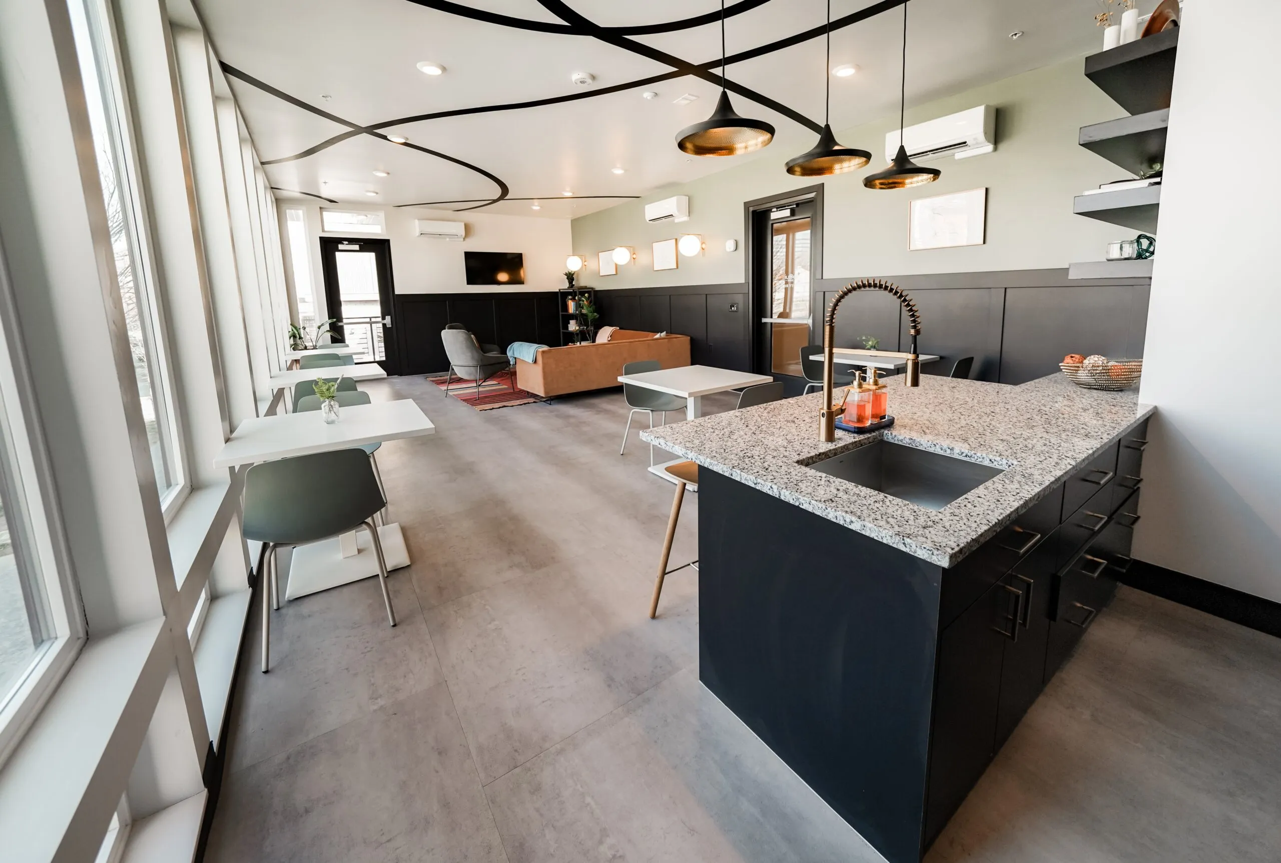 Spacious resident lounge at aQui355 apartments in Salt Lake City, UT, featuring a communal kitchen island, seating areas, and large windows with natural light.