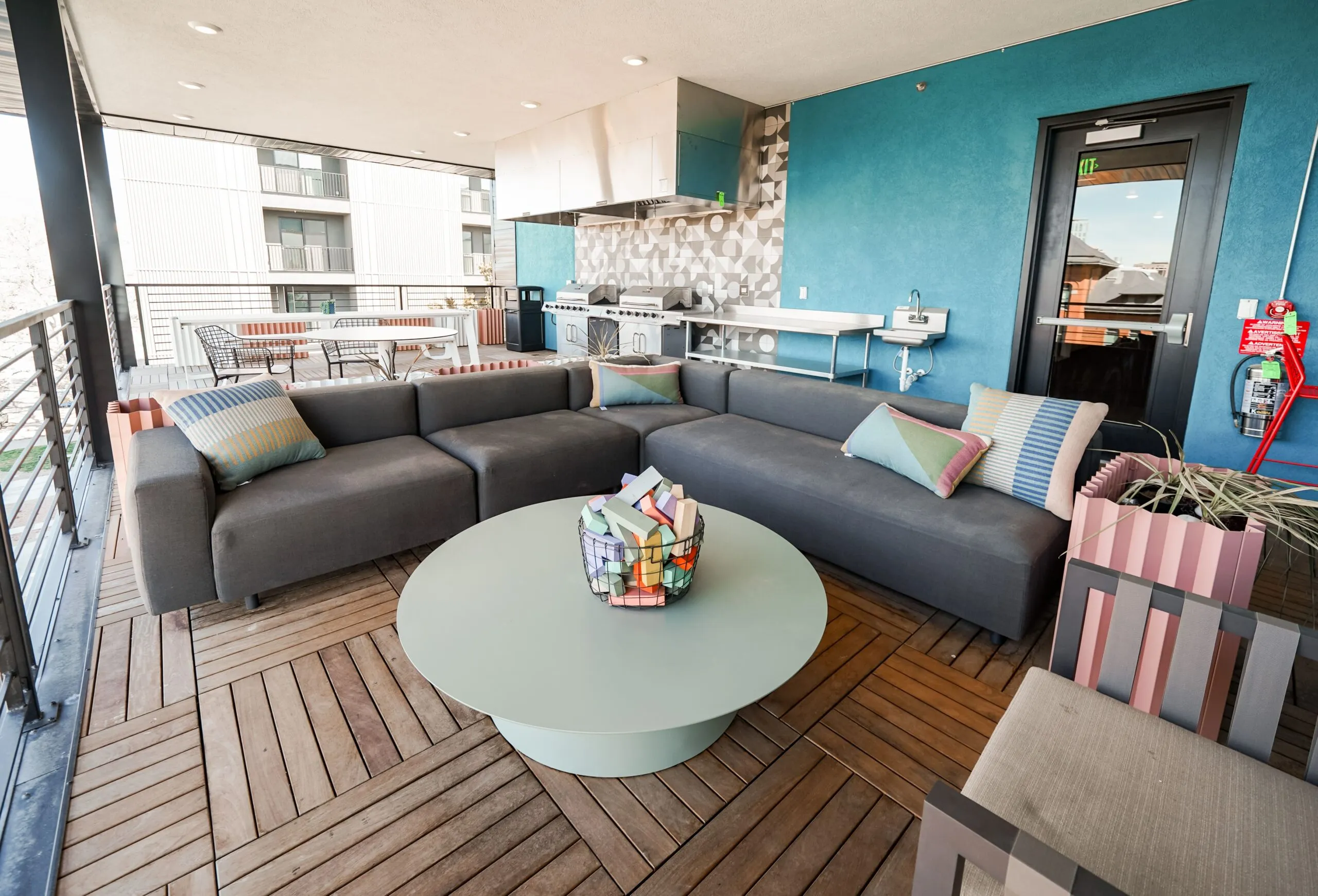 Covered outdoor lounge area with comfortable sofas and an outdoor kitchen at aQui355 apartments in Salt Lake City, Utah, perfect for relaxation and grilling.