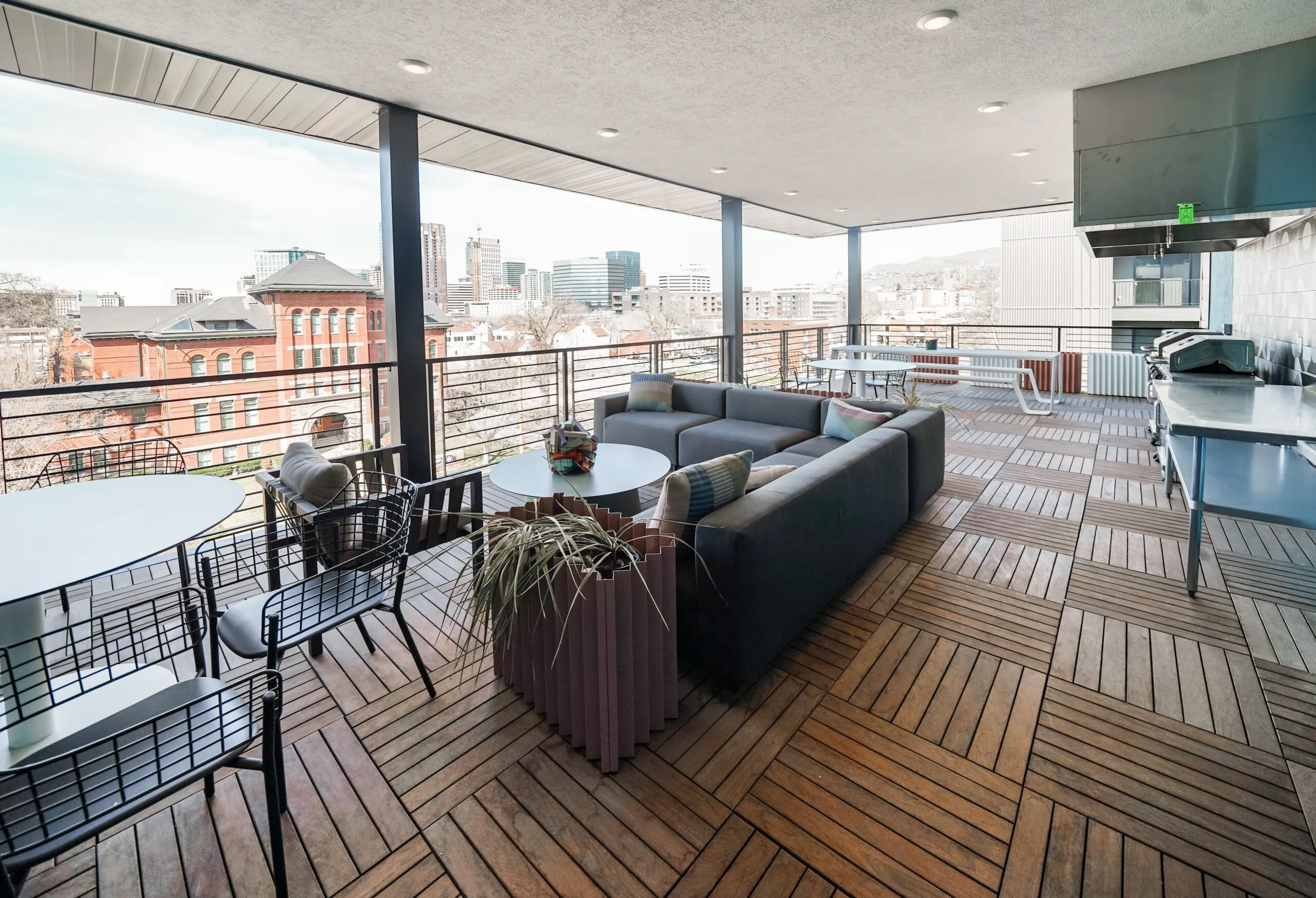 Expansive outdoor terrace at aQui355 apartments in Salt Lake City, UT, featuring lounge seating, dining tables, outdoor kitchen, and urban views.