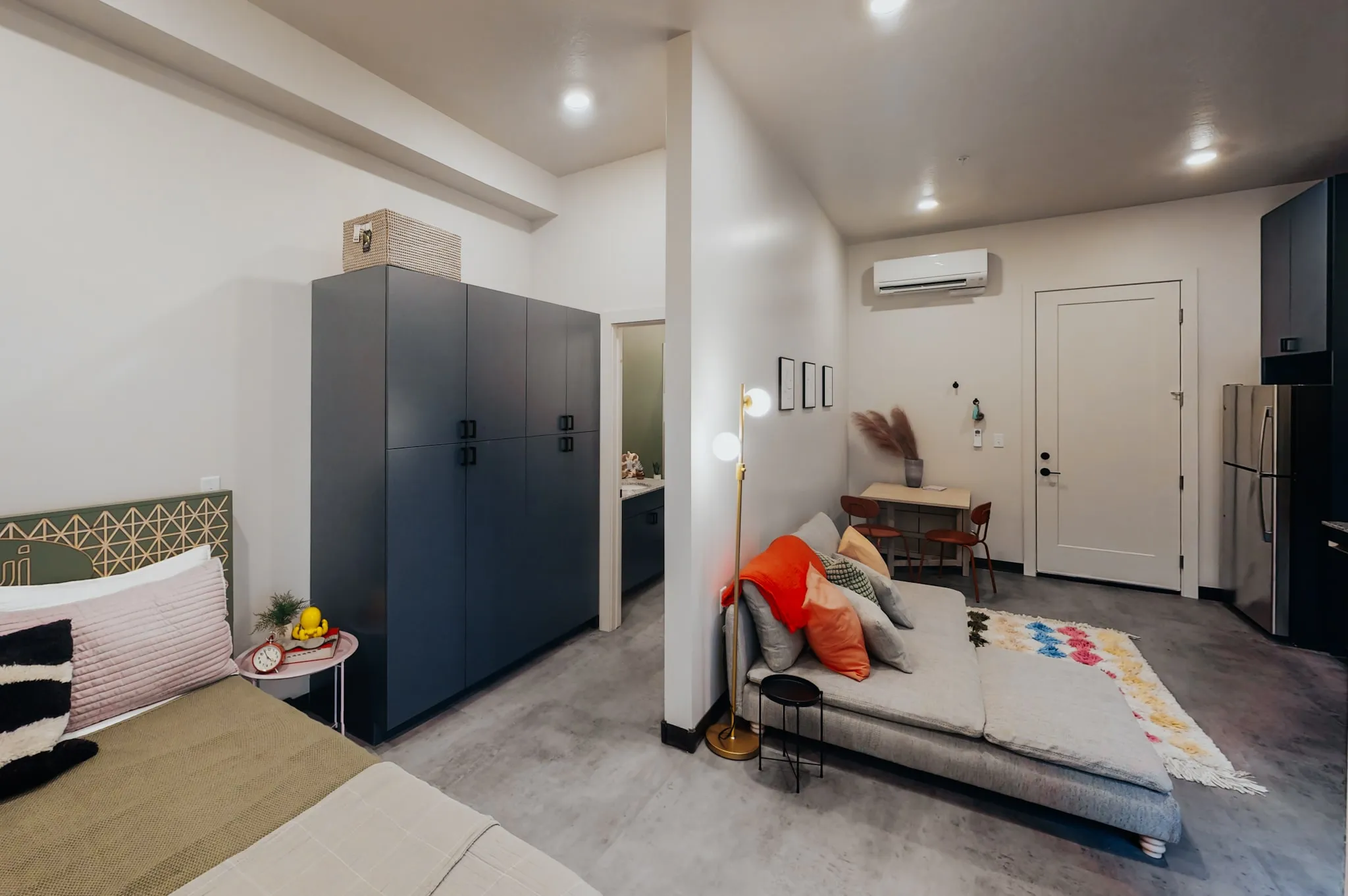Panoramic view of a studio apartment at aQui355 in Salt Lake City, UT, showcasing integrated living, sleeping, and kitchen areas with ample storage.