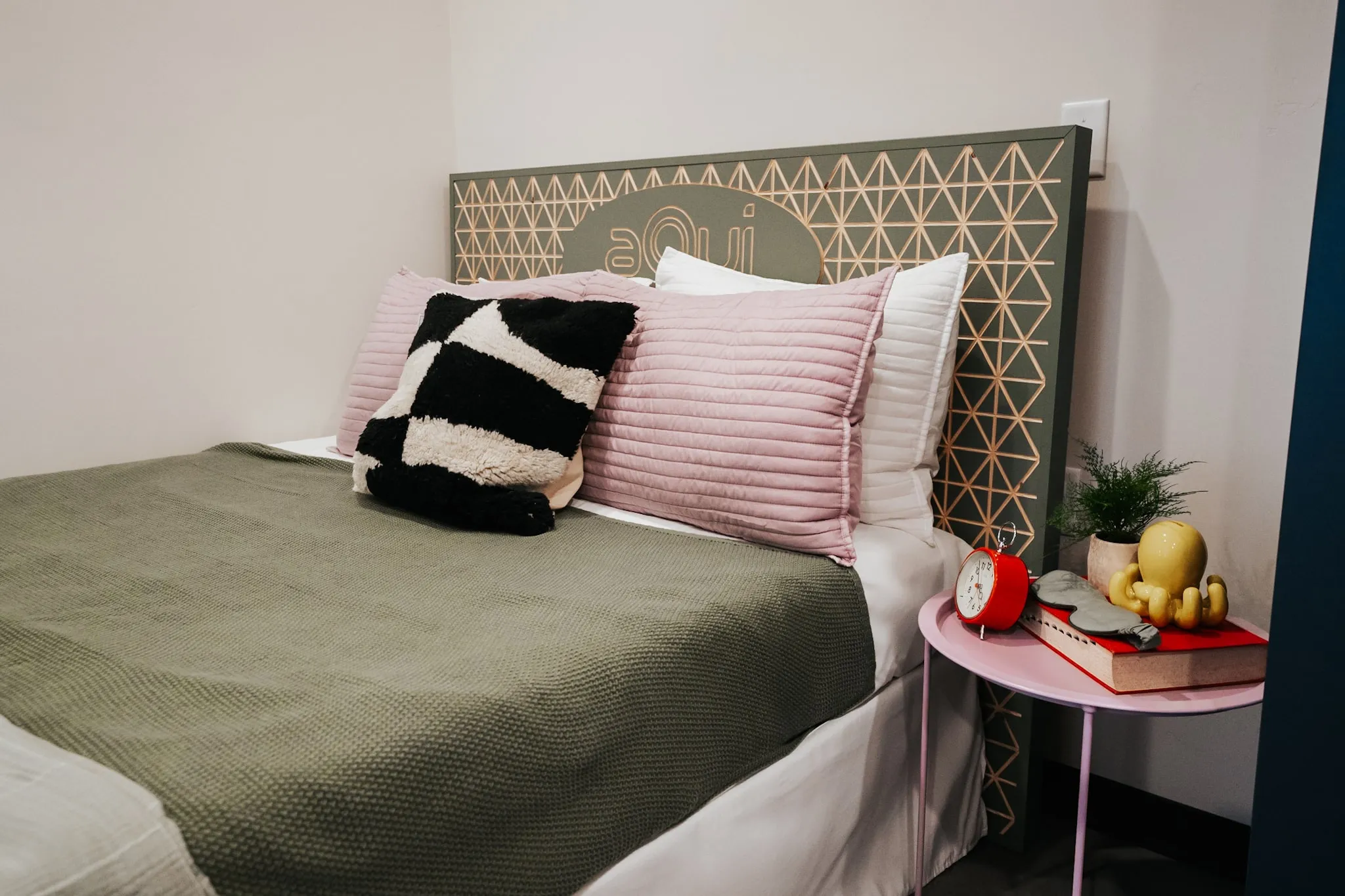 Close-up of a stylish bedroom with a unique headboard and modern decor in an apartment at aQui355, Salt Lake City, Utah.