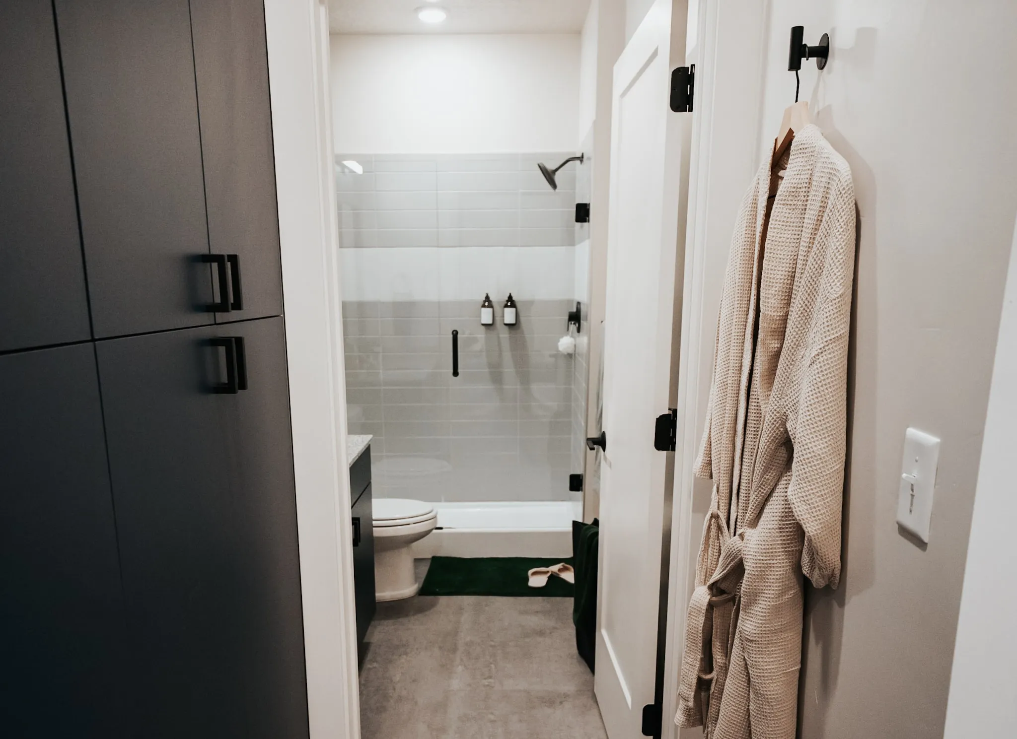 Modern bathroom with a walk-in shower and a glimpse of dark cabinetry, in an apartment at aQui355 in Salt Lake City, UT.