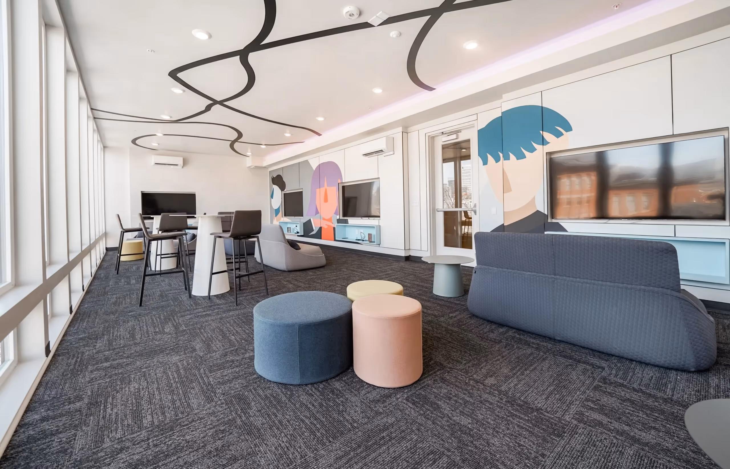 Vibrant game room with multiple large screen TVs, lounge seating, and colorful murals at aQui355 apartments in Salt Lake City, UT.