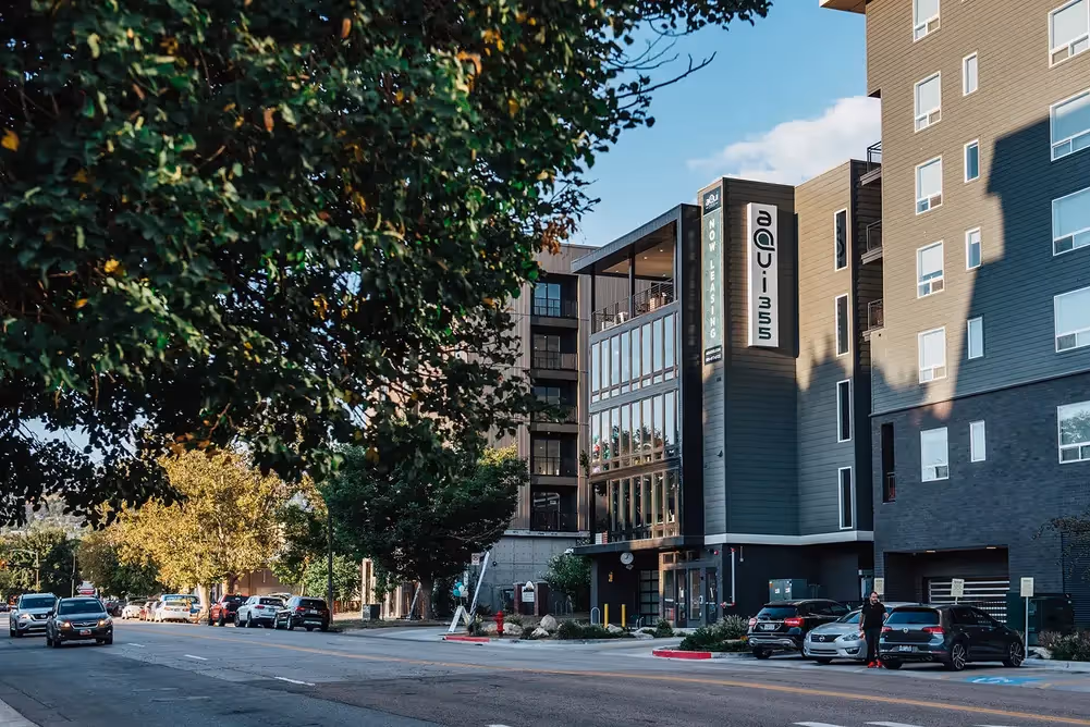 Modern aQui355 apartment building exterior in Salt Lake City, Utah, with contemporary architecture, large windows, and a vibrant street view.