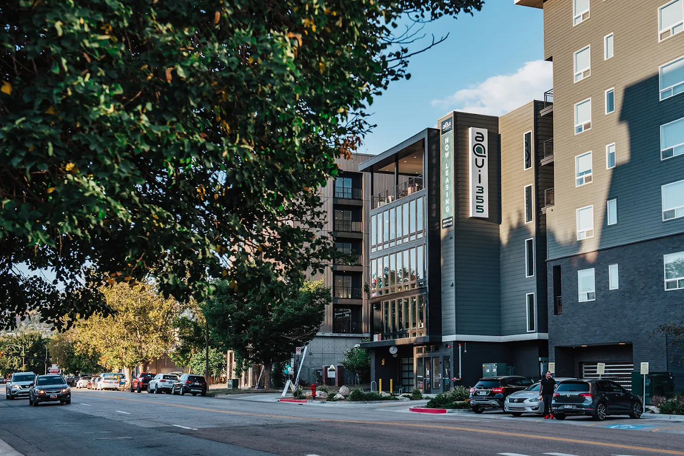Two happy women laughing and enjoying drinks outdoors at a bar or restaurant, representing the vibrant social life and local attractions near aQui355 apartments in Salt Lake City, Utah.