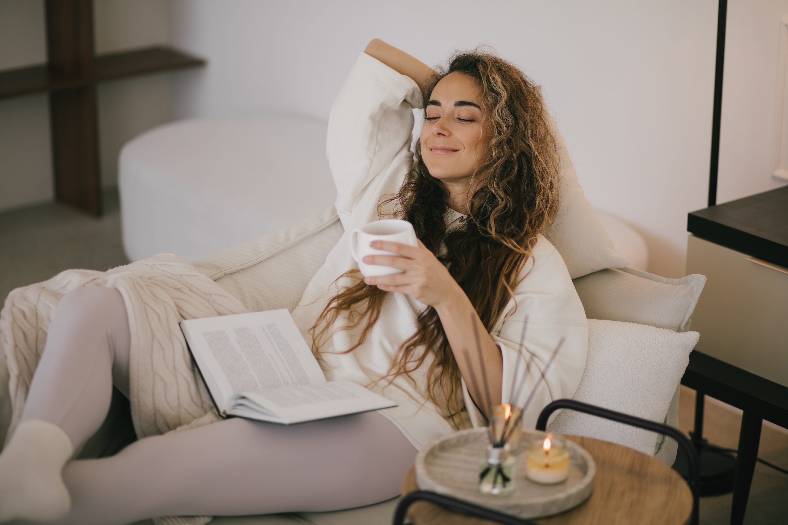 Resident relaxing with coffee and a book in a cozy armchair at aQui355, Salt Lake City