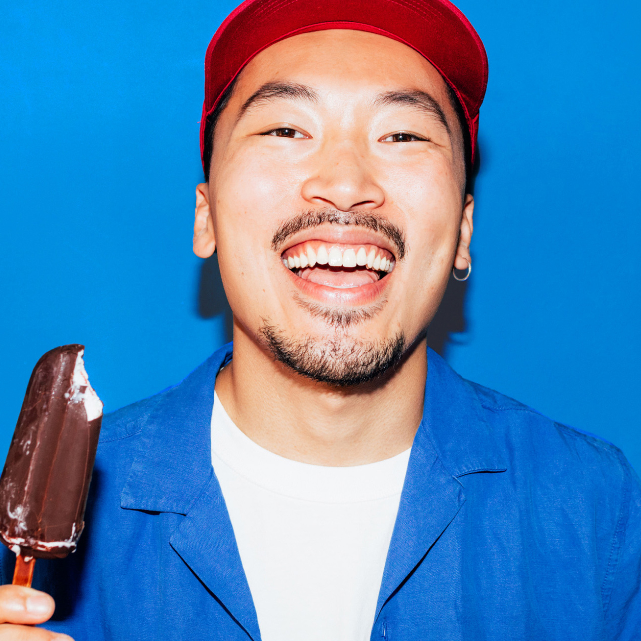 Image of man smiling while holding a icecream popsicle