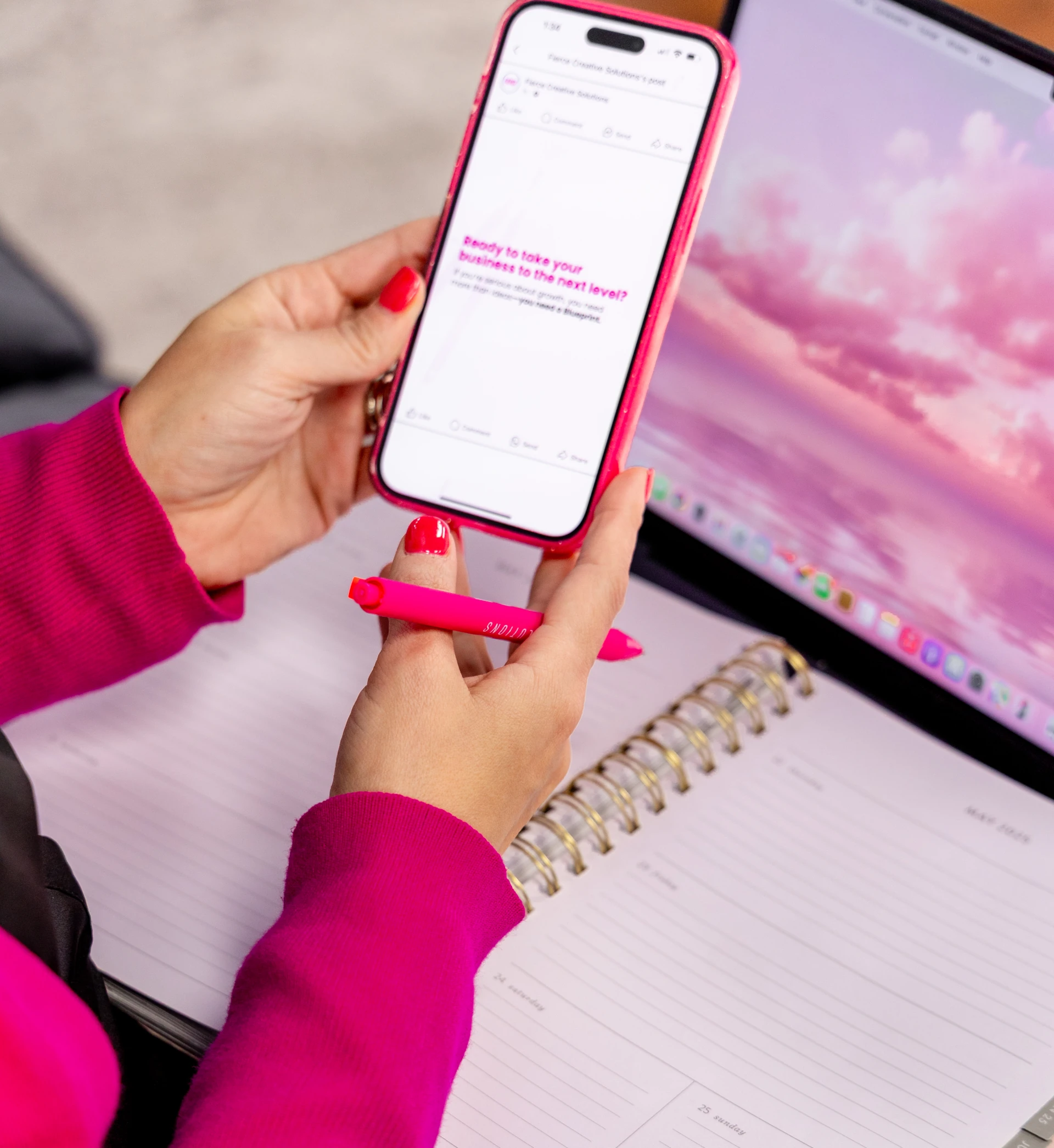 woman looking at phone, with a notebook and laptop on her lap