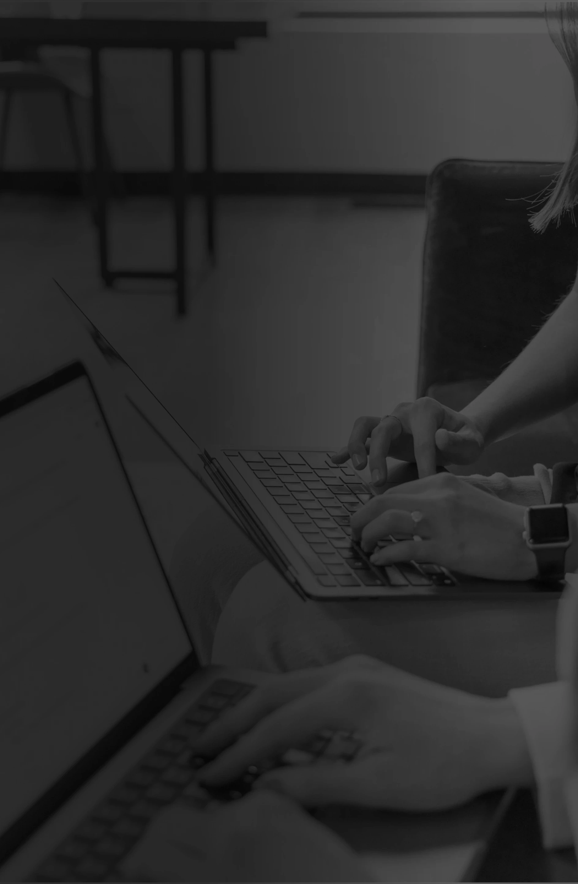 two people working on separate laptops grayscale gradient