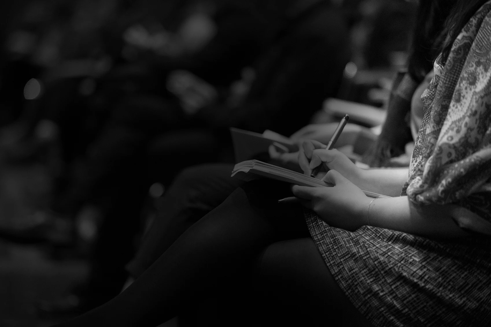 crowd of people sitting with notebooks in hand writing with gradient