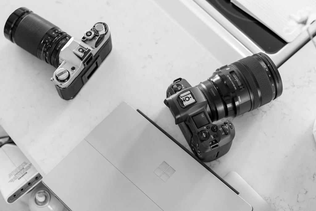 cameras sitting next to laptop on table