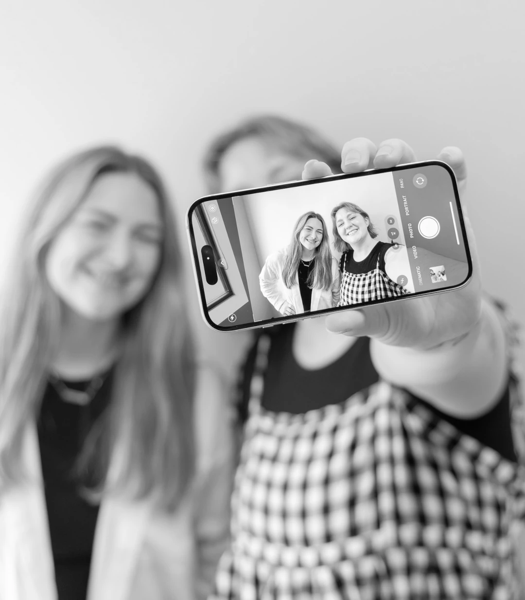 two women holding phone in front taking selfie