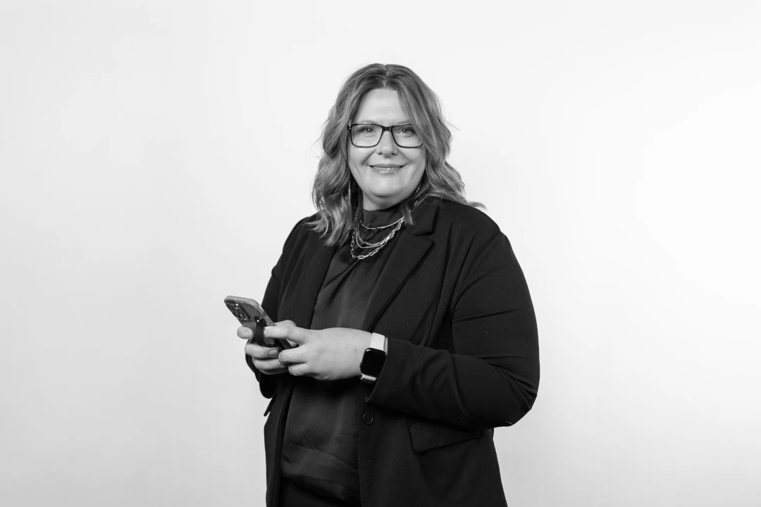 woman smiling at camera while holding cell phone