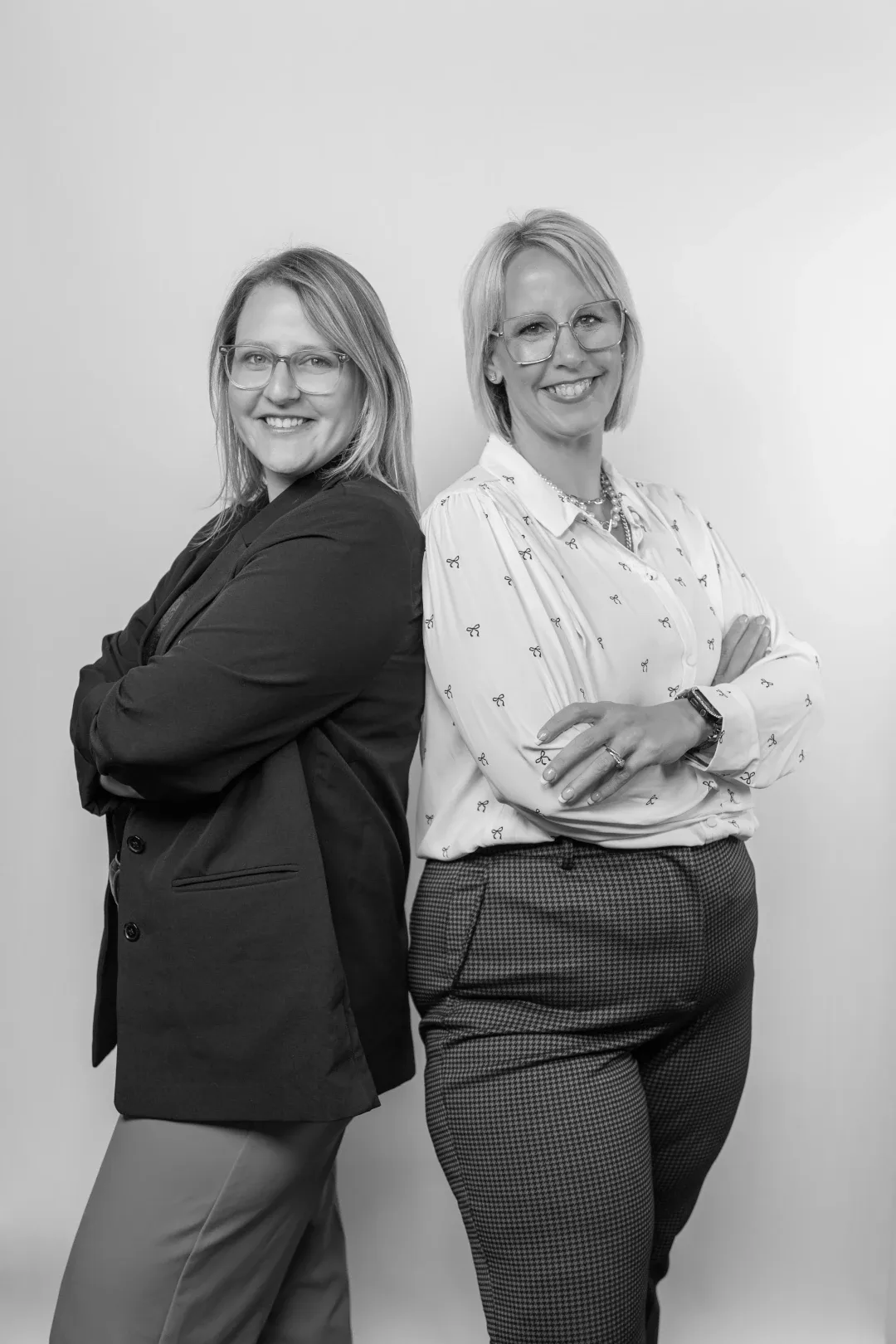 two women back to back with arms crossed