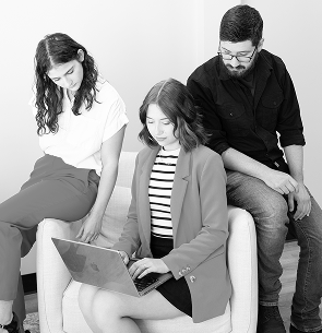 Three professionals, two women and one man, working together with a laptop in an office setting.
