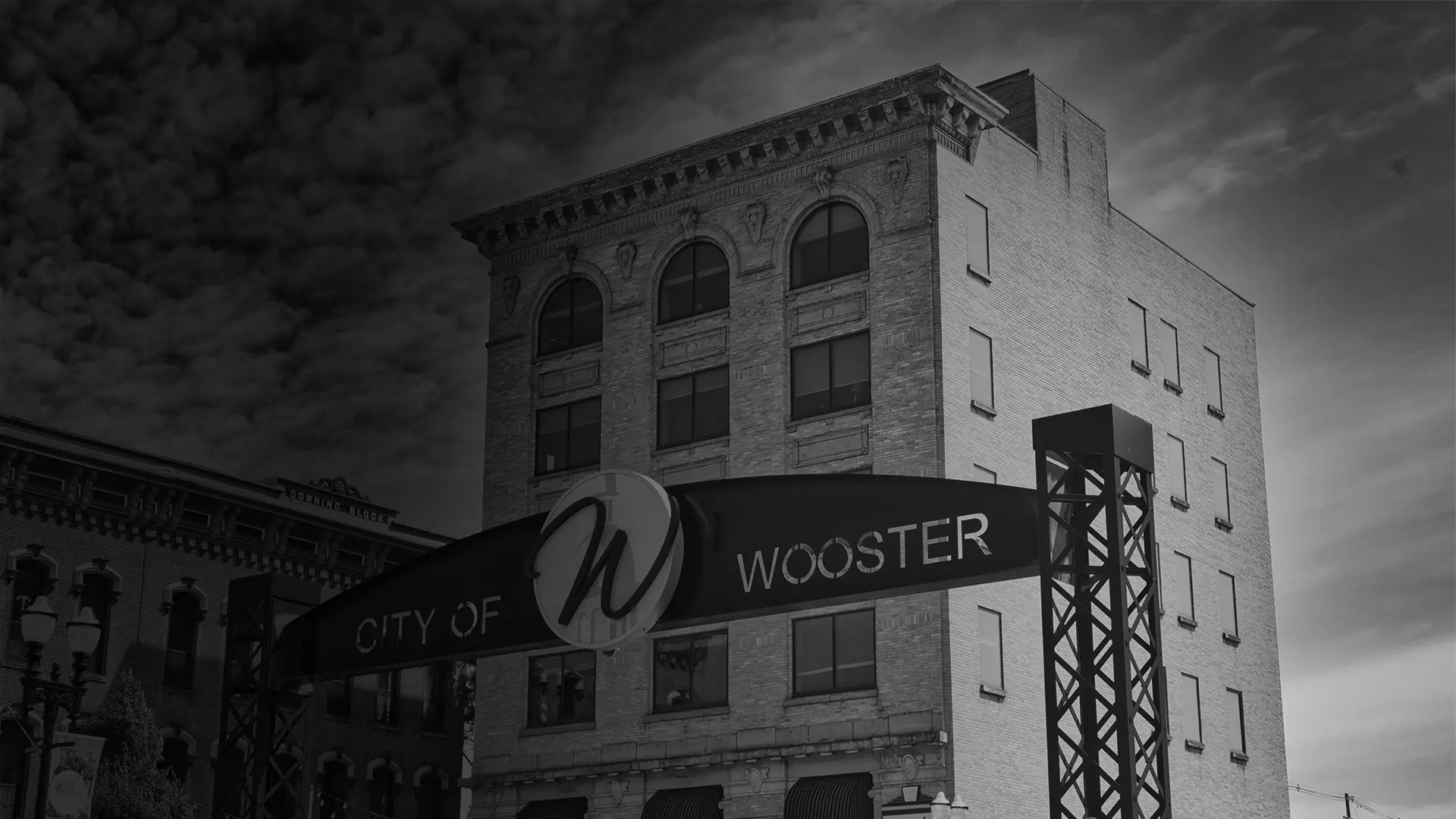 Historic courthouse building with a clock tower, flags, and surrounding trees in black and white.