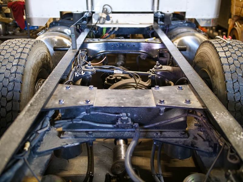 Close-up view of a tow truck’s rear chassis and suspension system, showing tires, frame, air lines, and suspension components. 