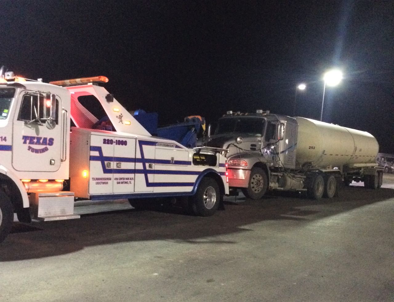 Heavy-duty tow truck hauling disabled semi truck at industrial yard, showcasing professional recovery services and commercial fleet support operations Texas.