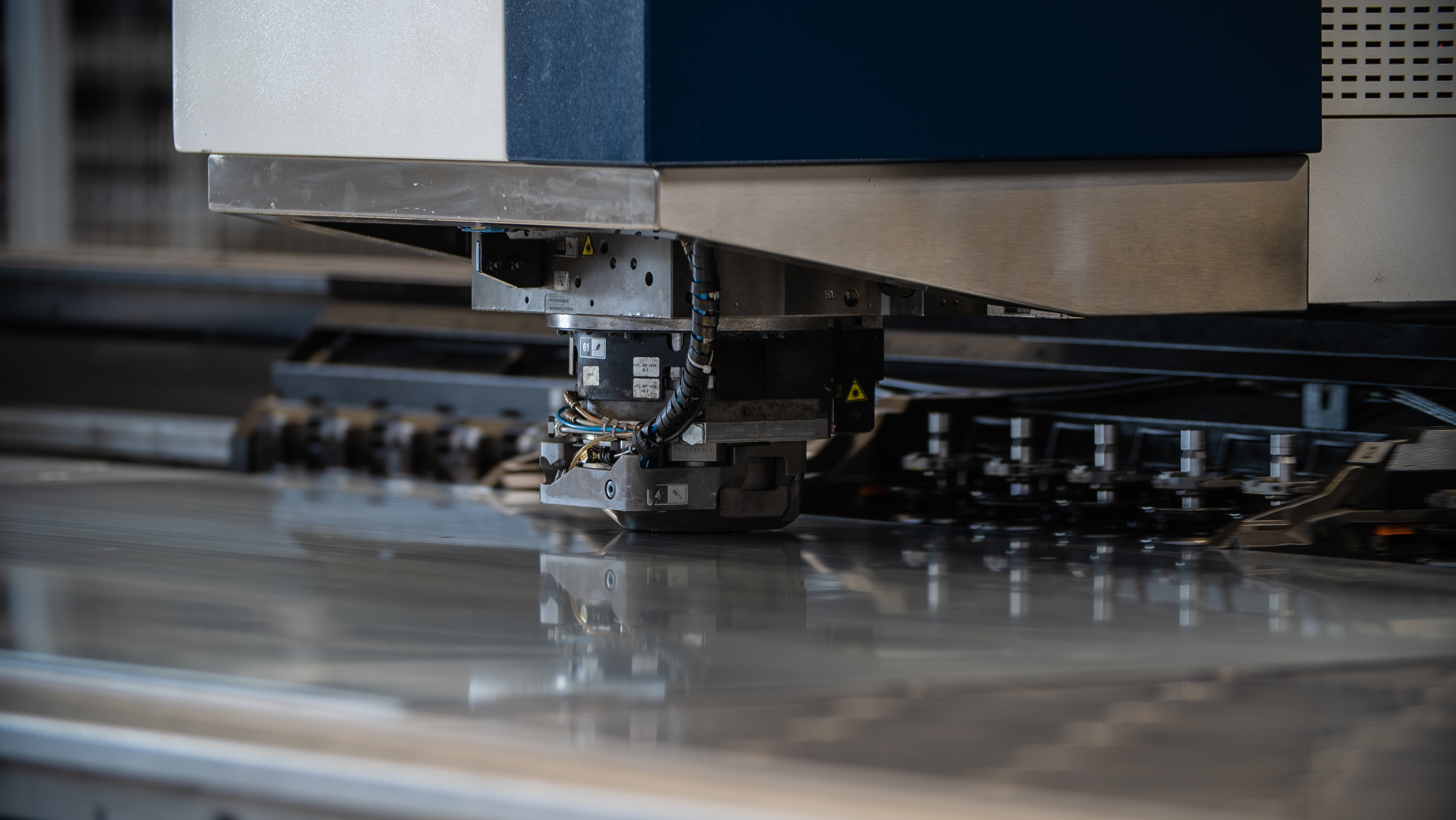Tête de poinçonneuse CNC en production sur une tôle