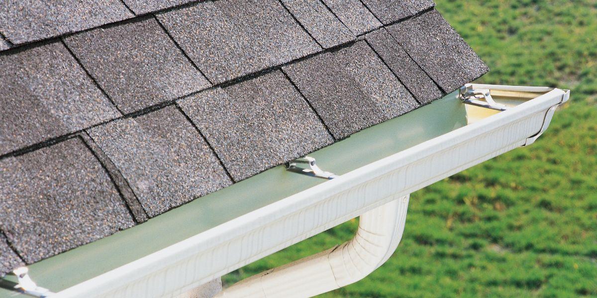 Contractor installing a mesh gutter guard on an asphalt shingle roof in Northeast Ohio