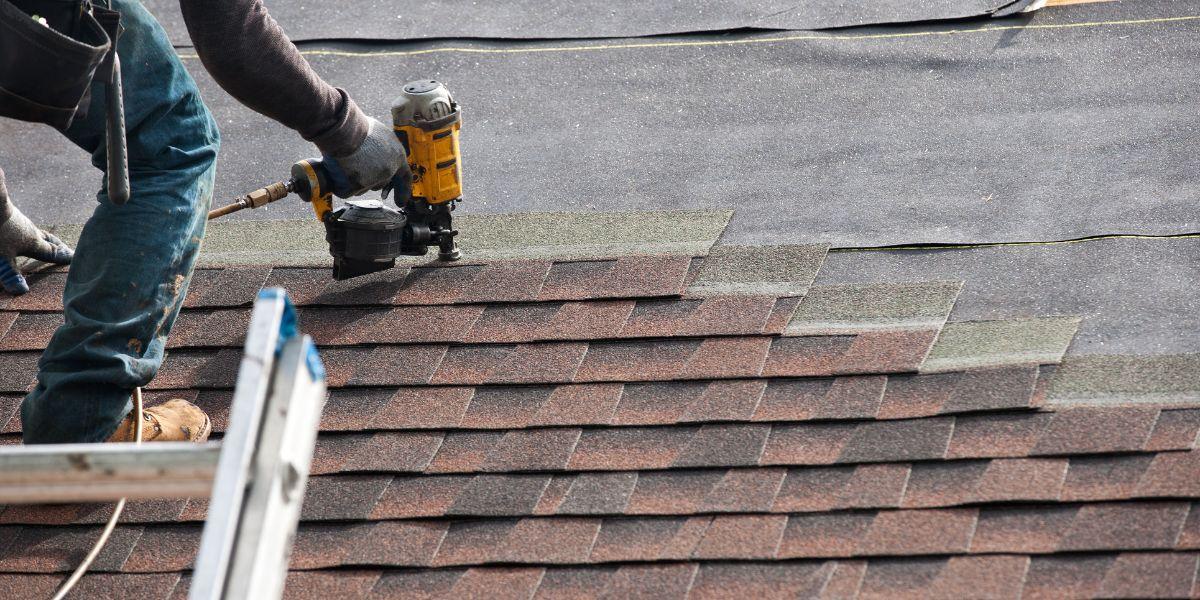 Roofing contractor installing GAF asphalt shingles during a residential roof replacement using proper installation techniques and roofing underlayment.