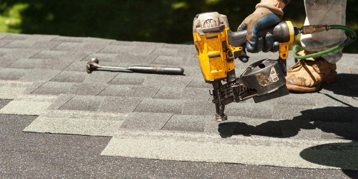 Roofing contractor uses a pneumatic nail gun to install architectural asphalt shingles during a Northeast Ohio residential roof replacement.