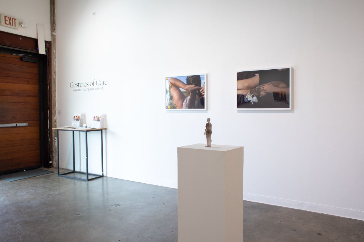 Art gallery room with projector displaying abstract shapes on left wall and framed artworks on right wall, including a round mirror.