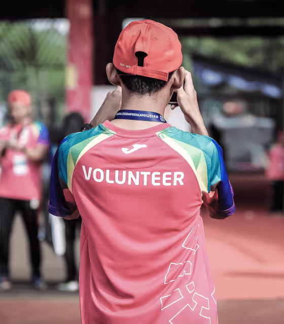 A man wearing a red shirt with the word volunteer on it.