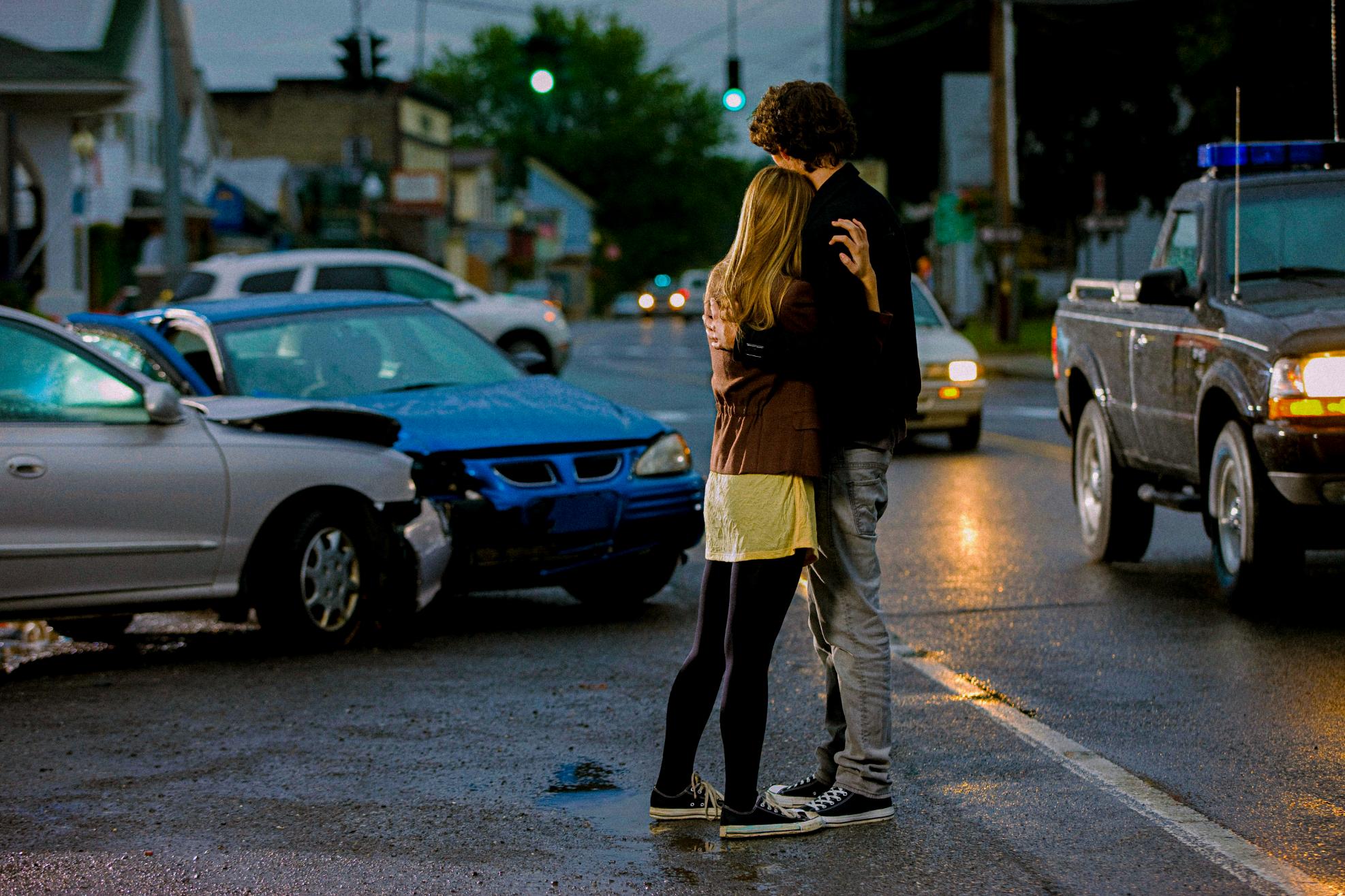 Two people hugging in an accident scene