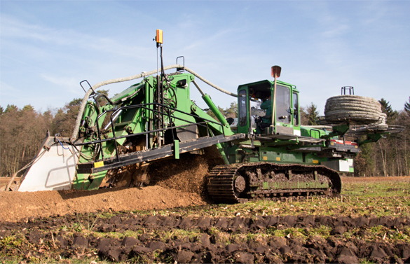A green tractor with a large tire and a hose attached to it.