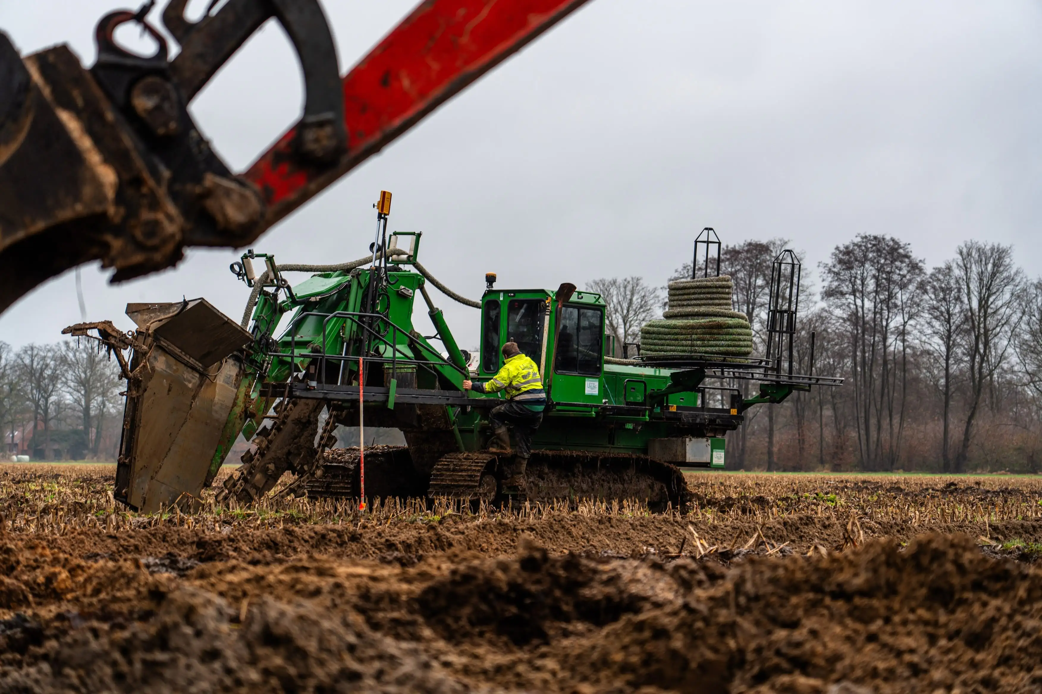 A green tractor with a man in a yellow vest operating it.
