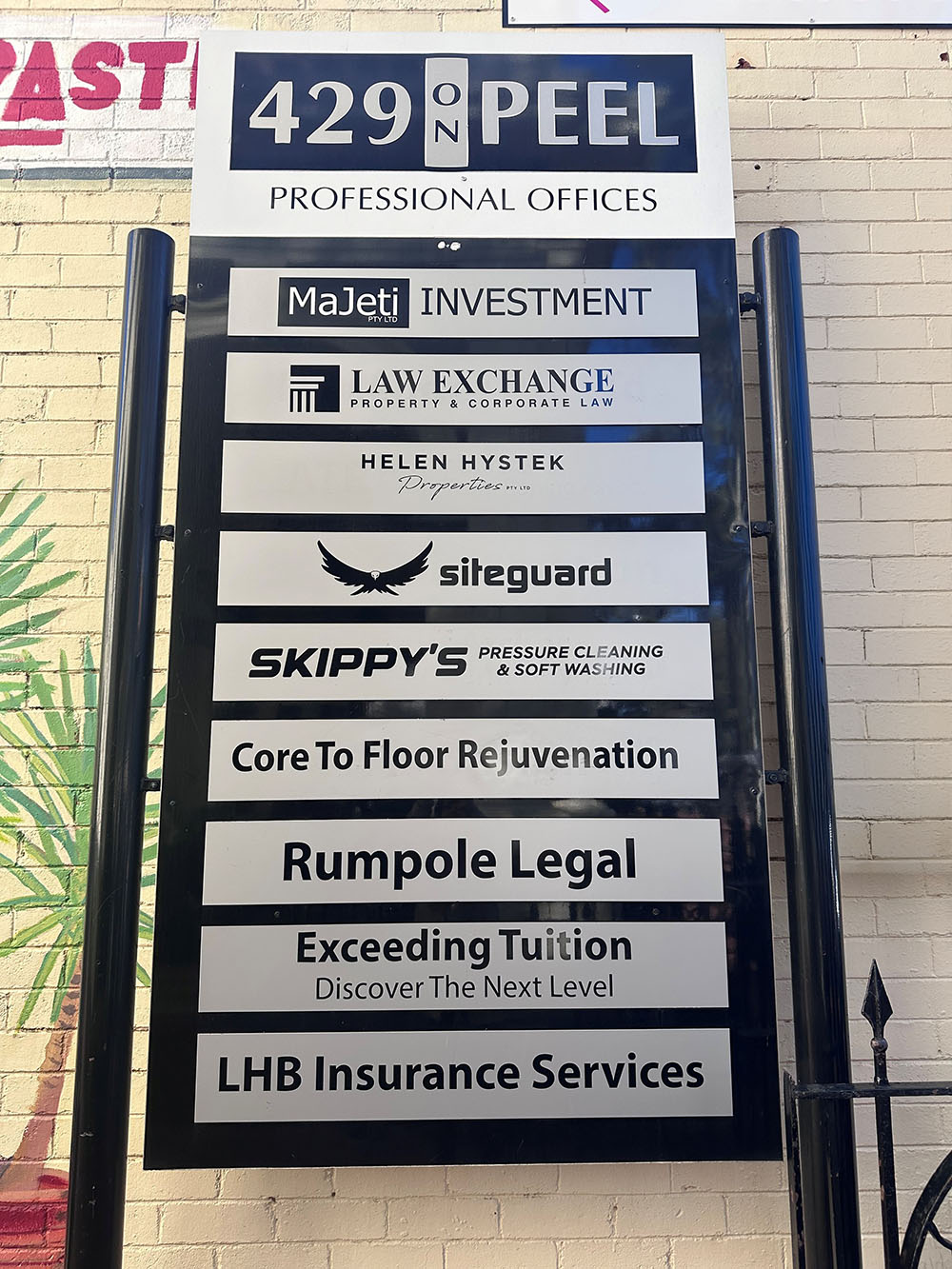 Sign listing professional offices at 429 on Peel including investment, law, cleaning, legal, tuition, and insurance services.