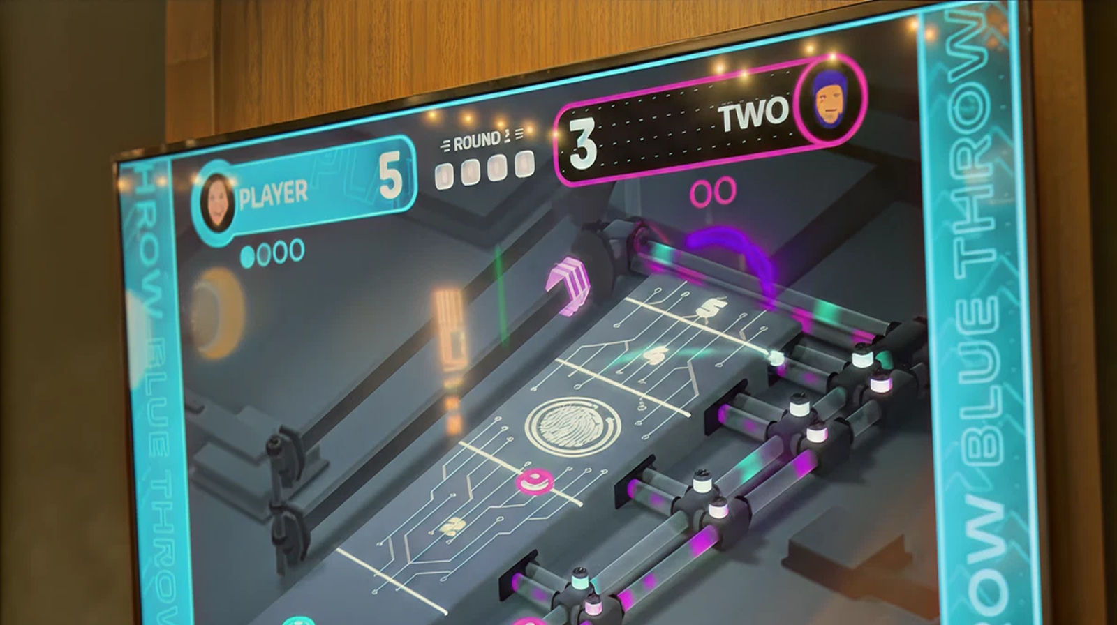 Electronic tabletop game screen showing two players with scores 5 and 3, neon-lit circuits, and mechanisms.