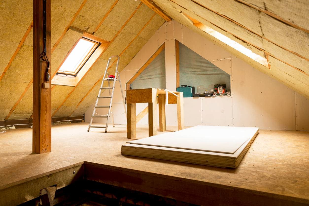 Pose d'isolant dans des combles aménagés, améliorant l'efficacité énergétique de la maison en réduisant les pertes de chaleur